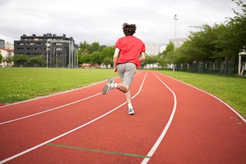 Full length rear view of a casuasian male young athlete sprinting training in a running track