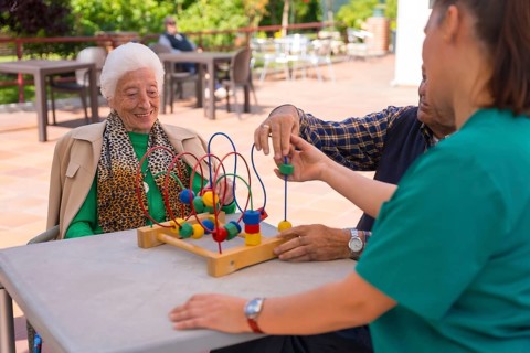 Two elderly people in the garden of a nursing home or retirement home playing with games to improve