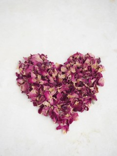Red heart made of rose petals on beige background. Romantic and love concept for Valentine's Day
