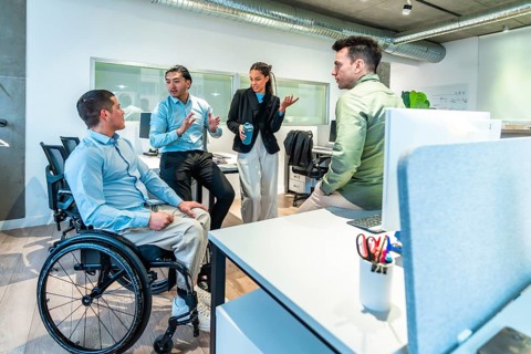 Business team discussing during a meeting in a modern office, with a disabled colleague actively