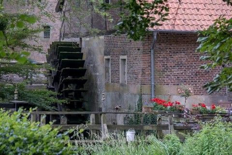 Old watermill with water wheel and blooming flowers in a rural setting, Haus Welbergen,