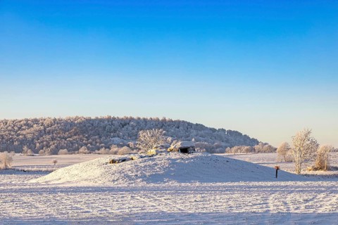 Megalith grave from Stone Age on a hill in a rural landscape with snow and frost on a cold winter