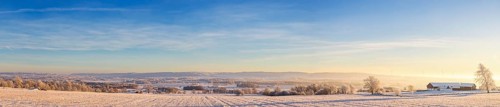 Panoramic landscape view of a rural winter landscape with farms and snowy fields on a cold winter