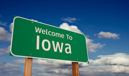 Welcome to iowa green road sign over blue sky with some clouds