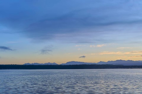 A calm lake surrounded by mountains and a blue sky during sunrise, Lake Mahinapua, Ruatapu, South