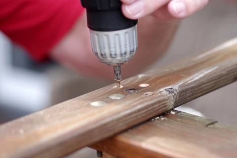 Cordless screwdriver, bit, screw, wood, finger, A screw is turned into the wood with a tool