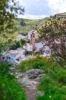 Idyllic village of Salares on the Sierra Tejeda with church in front of lush green hills and