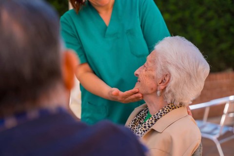 An older or mature woman with the nurse in the garden of a nursing home in a moment of love and