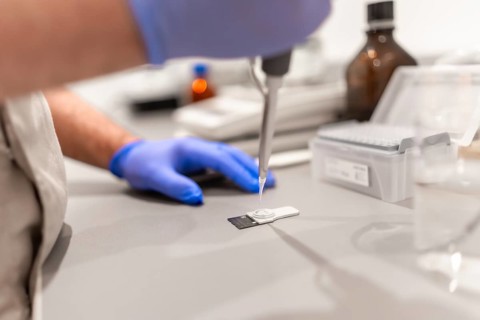 Side view close-up of an unrecognizable doctor using pipette to test samples in a pharmacy