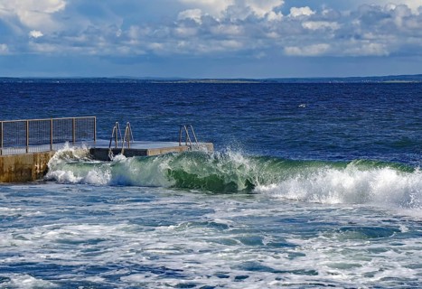 Waves rolling against a railing in the sea under a cloudy blue sky, Tönsberg, Oslofjord, Norway