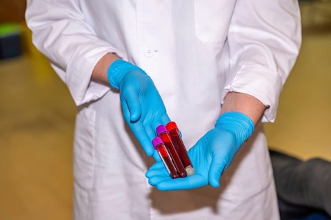 Unrecognizable doctor with blue gloves collecting samples of blood and holding them in a donation