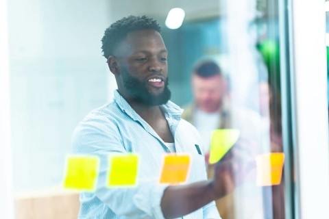Young manager writing notes on sticky notes during a brainstorming session with his colleagues