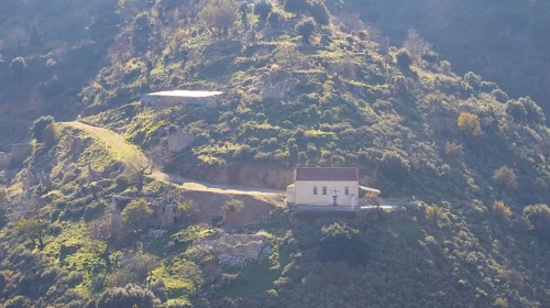 A secluded house on a sunlit hill with a dramatic mountain backdrop, Erymanthos Mountains,