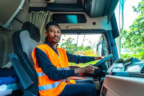 View from inside the vehicle of a african driver with reflective clothes sitting in a distribution