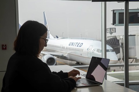 Denver, Colorado, A traveler works on a laptop while waiting for her flight at Denver International