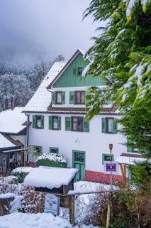 A white house with green shutters, surrounded by a snowy forest, Enzklösterle, Calw district, Black