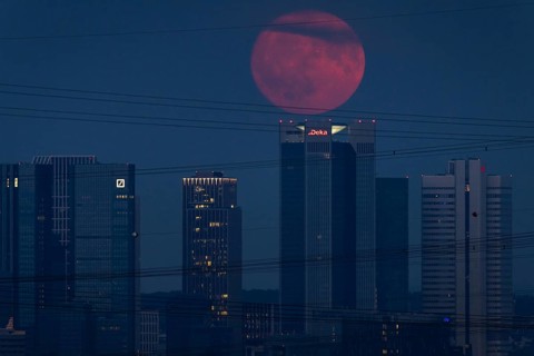 The red full moon passes over Frankfurt's banking skyline. Because of its reddish colour when it