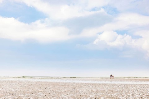 Children in swimsuits on a sand beach in low tide and a view to the horizon a summer day, Crozon