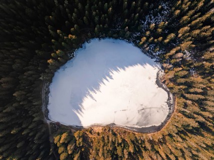 A bird's eye view of a frozen lake surrounded by forest in winter, Glaswaldsee, Bad