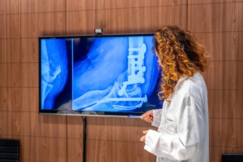 Rear view of a female doctor examining the hip of a patient using x-ray scan in the hospital