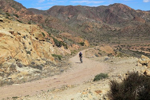 Person cycling in Cabo de Gata national park, Monsul, near San José, Almeria, Spain