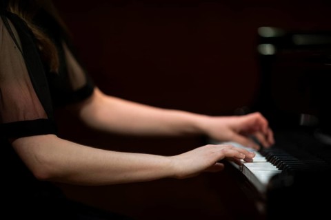Hands and arms of a young pianist playing on the keyboard of a Steinway & Sons grand piano,