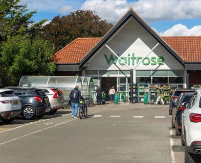 Customers shoppers walking towards entrance doorway of a Waitrose supermarket, Saxmundham, Suffolk,