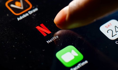 In this photo Illustration a person taps Netflix App icon on a tablet device on 24 May 2025 in New