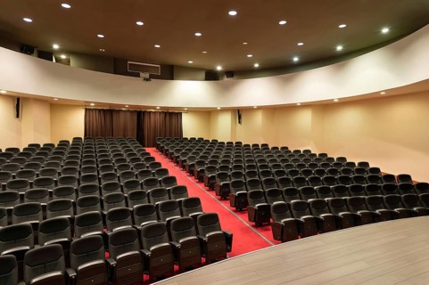 An empty convention center with rows of black seats and a vibrant red carpet. The space is well