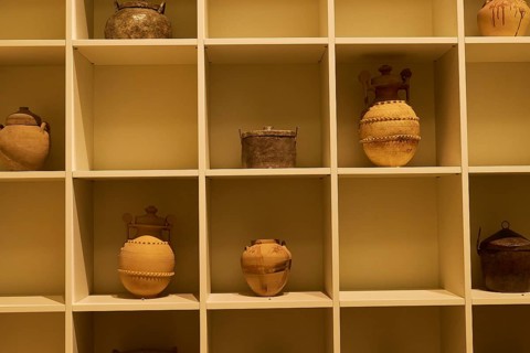 Spatial exhibition of clay jugs on a shelf with beige backlight, Patras Archaeological Museum,
