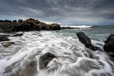Waves blaze on the beach, rocky coast with volcanic stones, long exposure, Playa de la Pequeña,