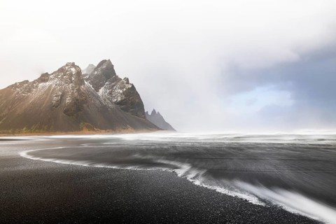 Sea waves on lava sandy beach against mountain backdrop, sea, snow, winter, Stokksnes, Vestrahorn,