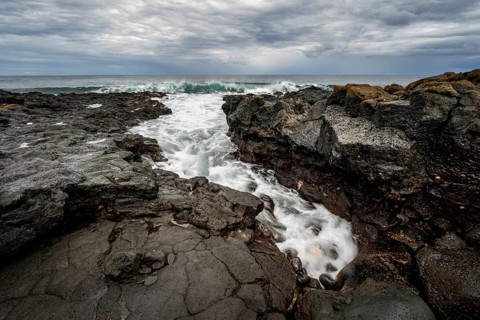 Waves blaze on the coast, rocky coast with volcanic stones, long exposure, Playa de la Pequeña,
