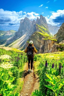 Hiker walking on a path enjoying the view of the odle mountains in the puez odle nature park