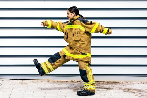 A young girl energetically wearing a firefighter suit, showcasing determination and strength. Her