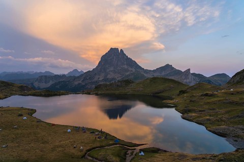 Stunning view of Midi d'Ossau in the French Pyrenees with a serene lake mirroring a colorful sunset