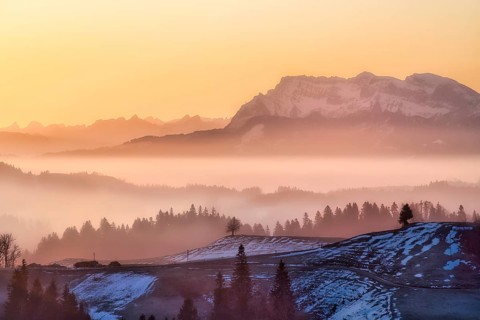 Misty morning atmosphere over hilly landscape with views of Mount Pilatus and Prealps, Entlebuch,