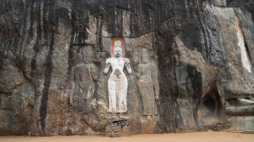 Ancient rock carvings in Sri Lanka depict serene figures against a rugged stone surface. The