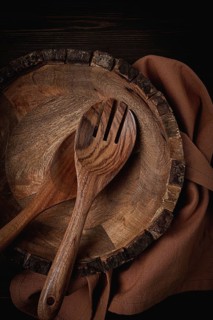 Wooden plate, handmade, with salad spoons, top view, on a wooden table, no people
