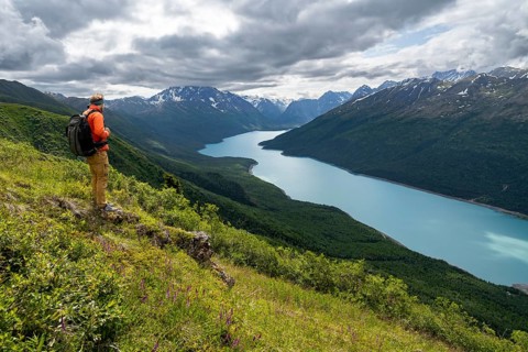 Mountaineer enjoys views of blue lake and mountains on Twin Peaks Trail, Eklutna Lake, Chugach