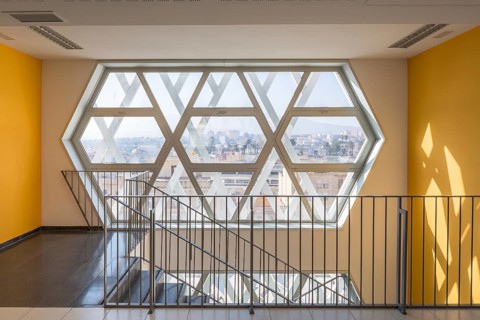 Interior of a modern auditorium with a unique hexagonal window design, casting geometric shadows on