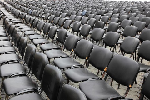 Chairs covered with gray plastic stand in rows in a function room, empty, vacant, seating