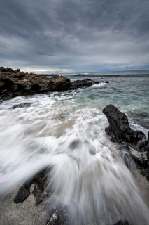 Waves blaze on the beach, rocky coast with volcanic stones, long exposure, Playa de la Pequeña,