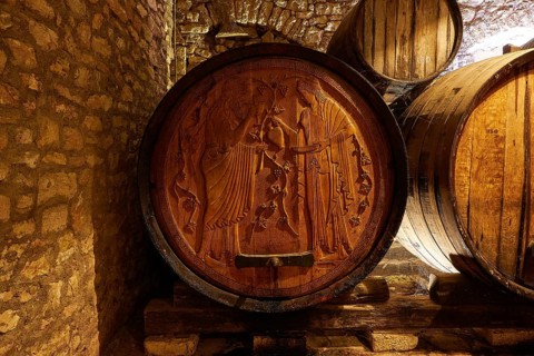 Detailed engravings on a wooden barrel in a rocky wine cellar environment, Achaia Clauss winery,