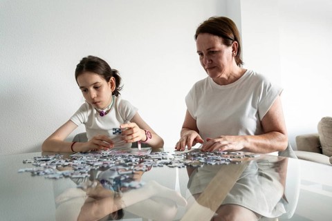 A mother and daughter, who has a tracheostomy, enjoy quality time together solving a puzzle at the