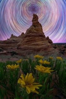 Captivating night sky star trails spiral above a rugged desert landscape in Coyote Buttes, Arizona.