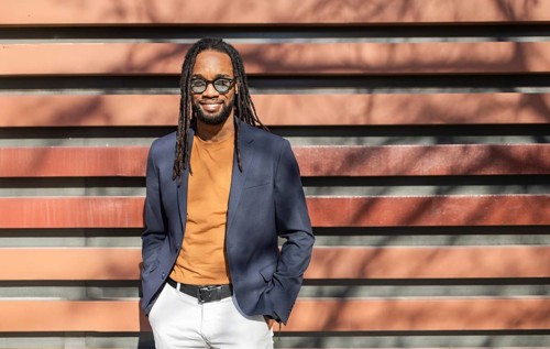 A business cuban man with dreadlocks, wearing sunglasses, exudes confidence in a blue blazer,