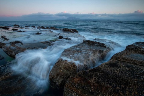 Tranquil sunset on the rocky coast of Tarifa, Cadiz, with waves gently washing over the rocks. The