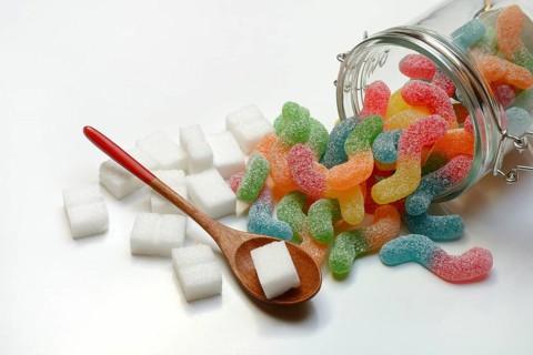 Lots of colorful jelly sweets in glass containers and sugar cubes, sugar consumption
