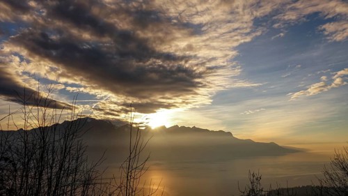 Stunning view of the sun setting over Lake Geneva with the silhouette of the French Alps in the